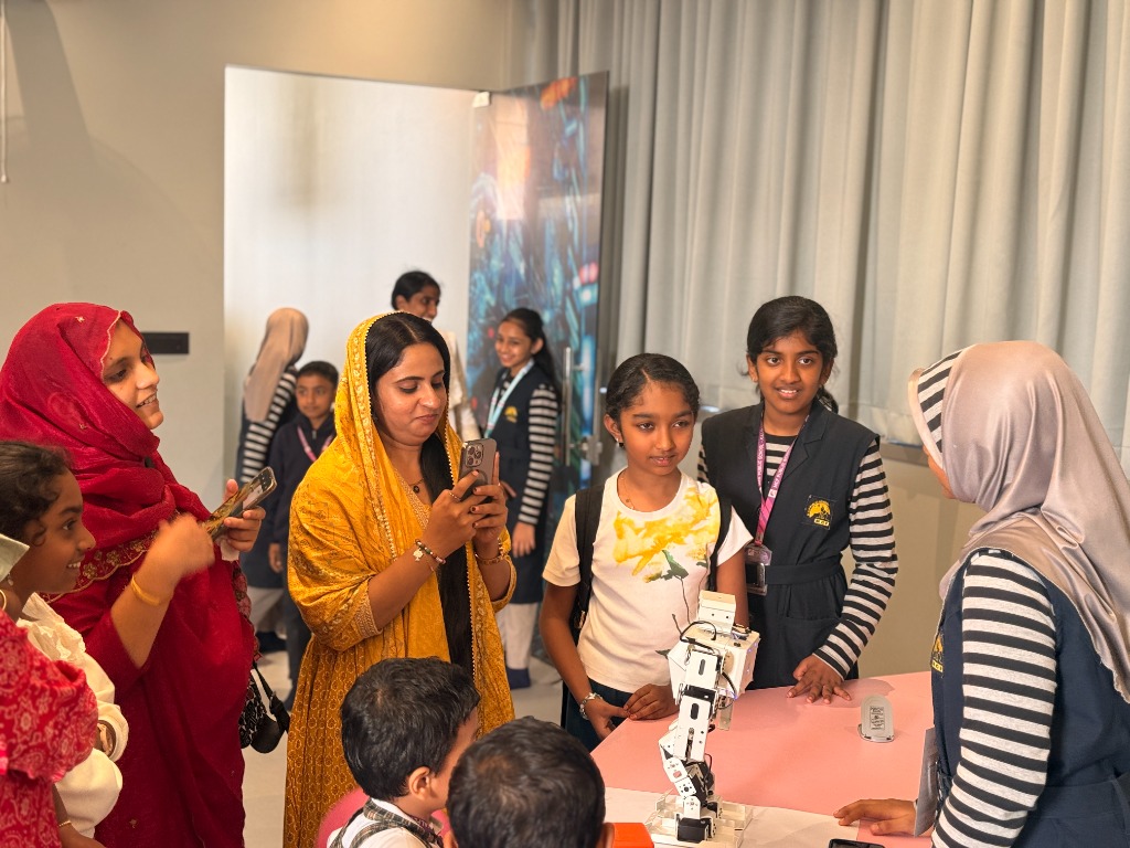 Women and students exploring humanoid robot on table